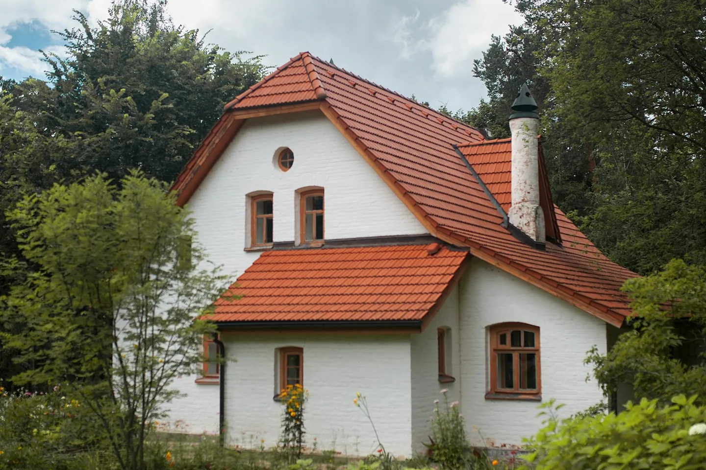Bela kuća sa crvenim krovom okružena zelenilom